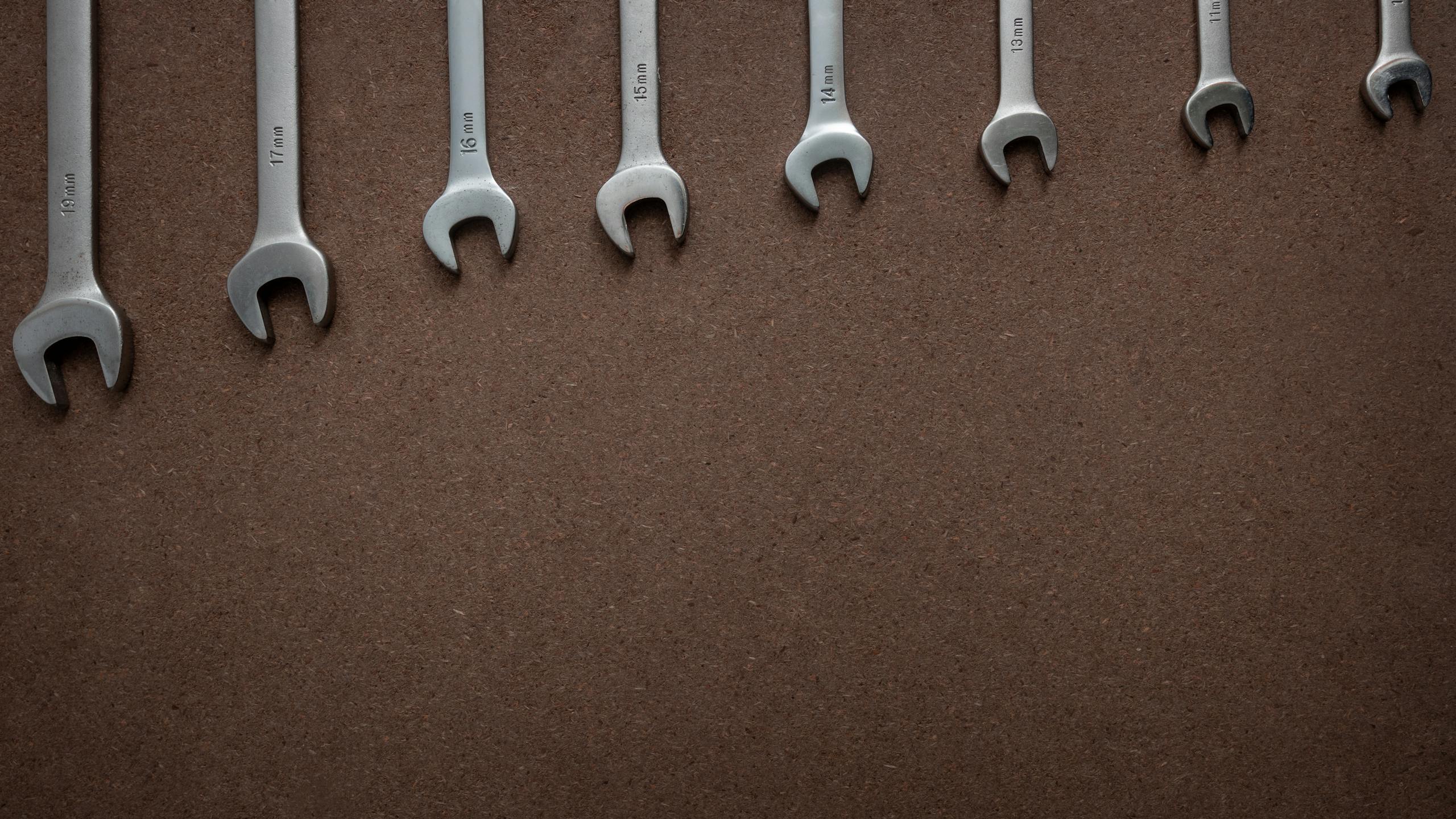 Top view of wrenches lined up on a textured brown surface, showcasing sizes.